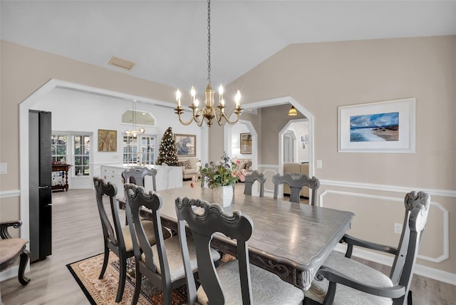 dining space featuring light hardwood / wood-style flooring, a chandelier, and lofted ceiling