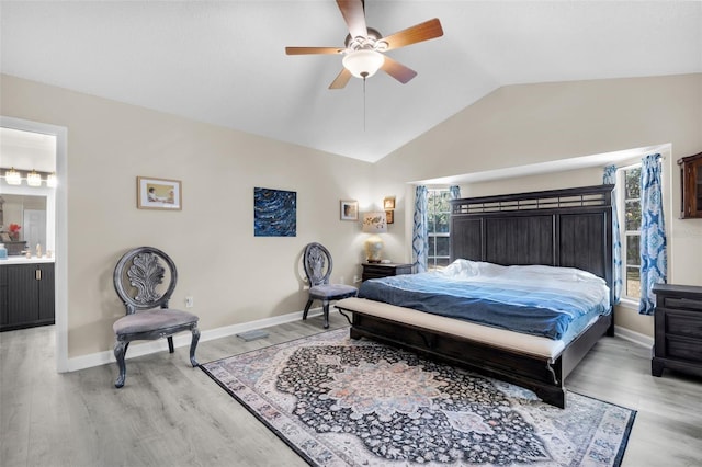 bedroom with light wood-type flooring, ensuite bath, ceiling fan, multiple windows, and lofted ceiling