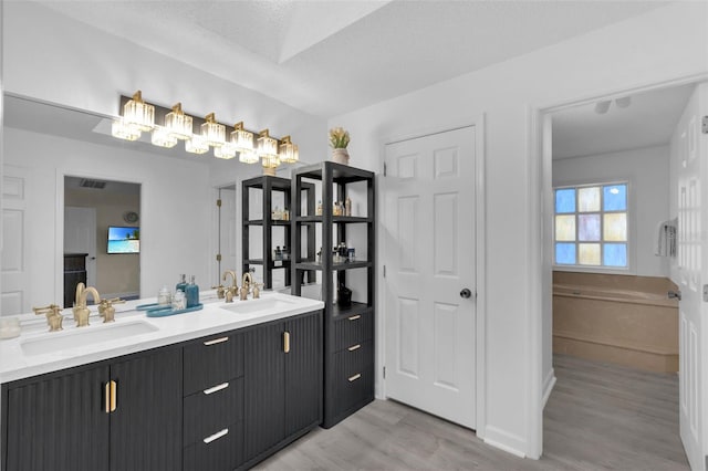 bathroom with hardwood / wood-style flooring, vanity, and a textured ceiling