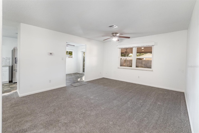 unfurnished room featuring plenty of natural light, dark carpet, and ceiling fan