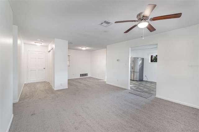 unfurnished living room with light carpet, a textured ceiling, and ceiling fan