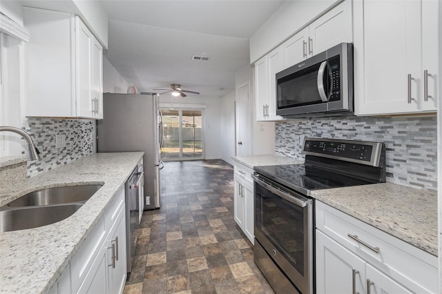 kitchen with light stone counters, sink, white cabinets, and stainless steel appliances