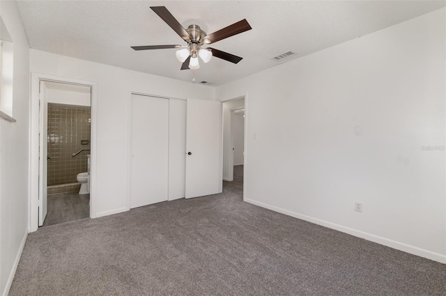 unfurnished bedroom featuring carpet, ensuite bath, a textured ceiling, ceiling fan, and a closet