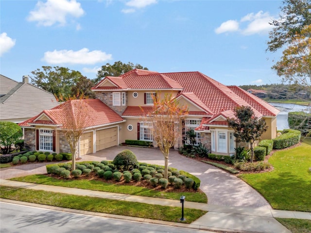 mediterranean / spanish-style home with a garage and a front lawn