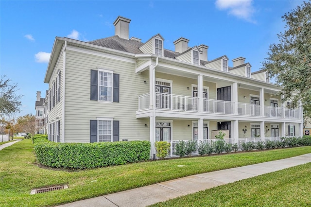 view of front of home with a balcony and a front yard