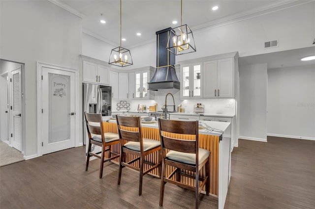 kitchen with white cabinetry, an island with sink, a breakfast bar area, and pendant lighting