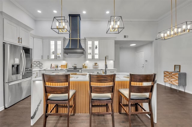 kitchen featuring white cabinetry, stainless steel fridge, wall chimney exhaust hood, and a center island with sink