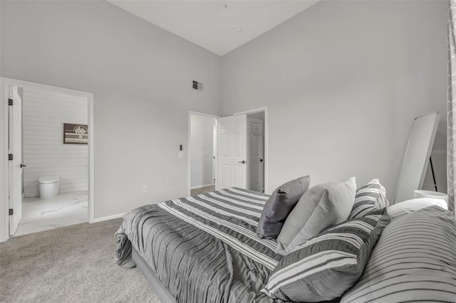 carpeted bedroom with connected bathroom and high vaulted ceiling