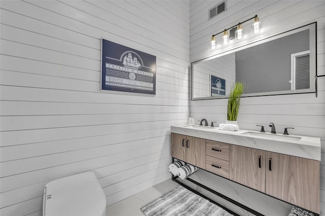 bathroom with vanity, toilet, and wood walls