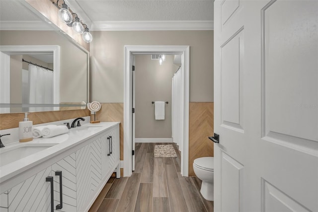 bathroom with hardwood / wood-style flooring, ornamental molding, vanity, and a textured ceiling