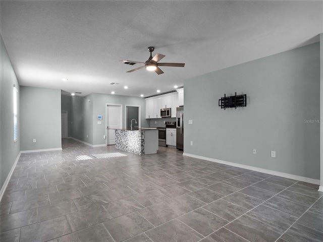 unfurnished living room with ceiling fan, sink, and a textured ceiling