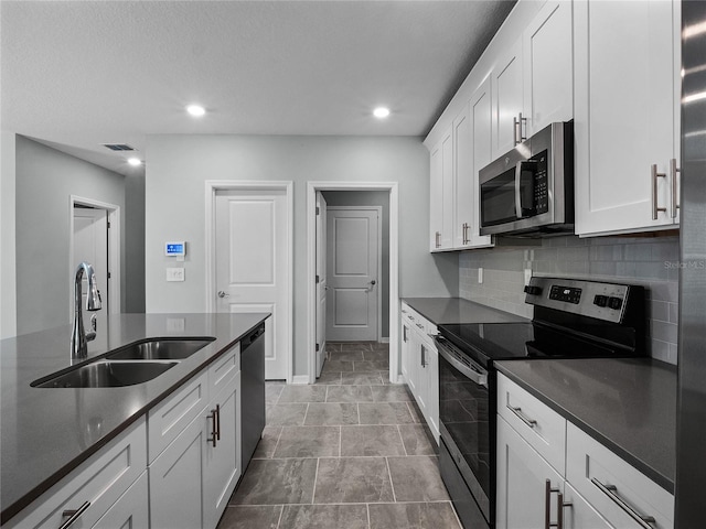 kitchen featuring tasteful backsplash, stainless steel appliances, sink, white cabinets, and light tile patterned flooring