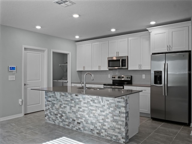 kitchen with a center island with sink, washer / clothes dryer, white cabinetry, and appliances with stainless steel finishes