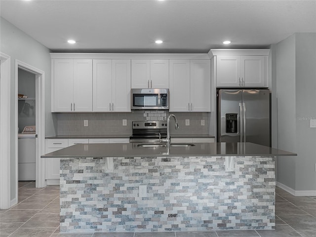 kitchen with a center island with sink, white cabinets, washer / clothes dryer, and appliances with stainless steel finishes