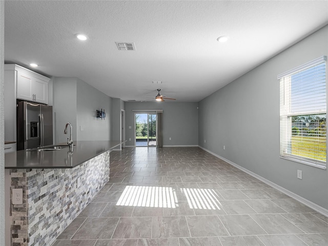 kitchen with white cabinetry, sink, ceiling fan, stainless steel fridge with ice dispenser, and a textured ceiling