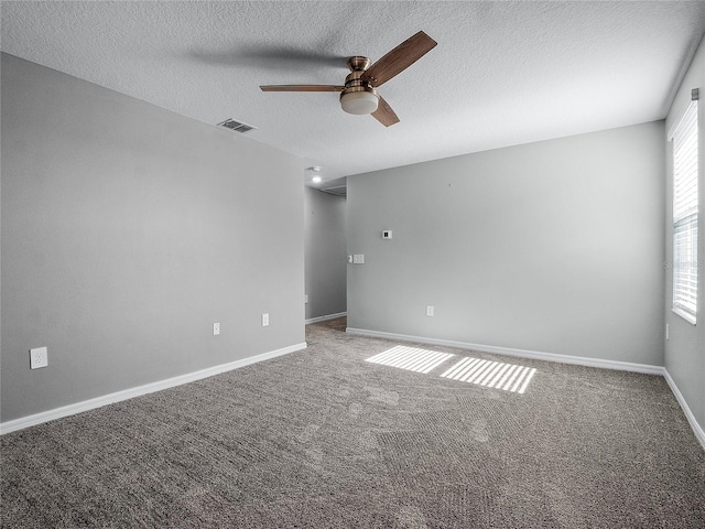 empty room with carpet flooring, ceiling fan, and a textured ceiling