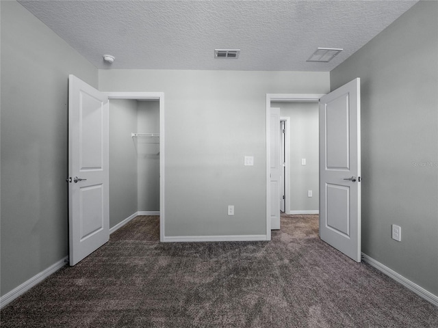 unfurnished bedroom featuring a closet, a textured ceiling, and dark colored carpet