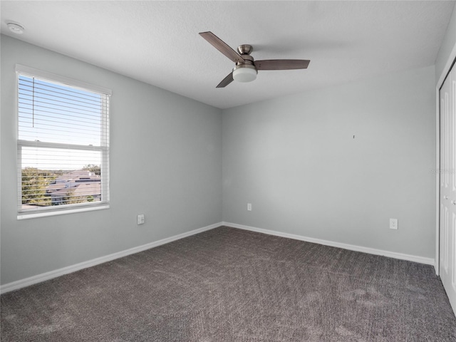 unfurnished room with dark carpet and ceiling fan