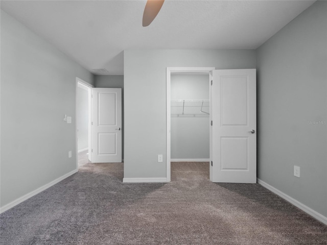 unfurnished bedroom with ceiling fan, a spacious closet, carpet floors, and a closet