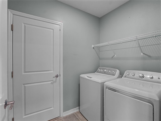 clothes washing area featuring washer and clothes dryer and light tile patterned flooring