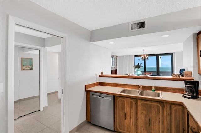 kitchen with stainless steel dishwasher, sink, light tile patterned floors, a chandelier, and hanging light fixtures