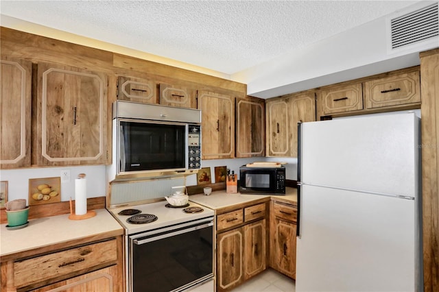 kitchen with light tile patterned floors, white appliances, and a textured ceiling