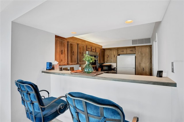 kitchen with kitchen peninsula, a kitchen breakfast bar, and white refrigerator