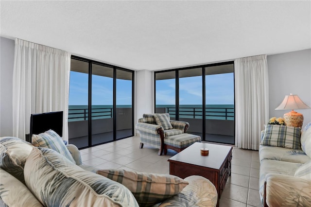 living room featuring a textured ceiling, a water view, floor to ceiling windows, and light tile patterned flooring