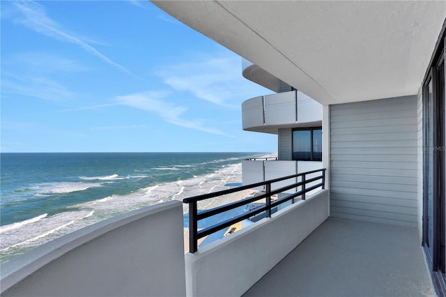 balcony with a water view and a view of the beach