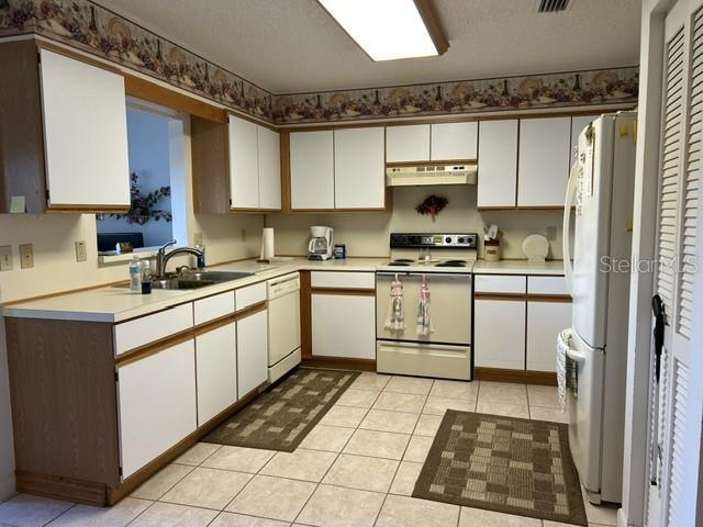 kitchen featuring white cabinets, sink, and white appliances