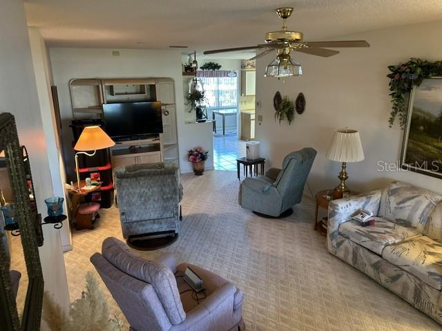 carpeted living room with a textured ceiling and ceiling fan