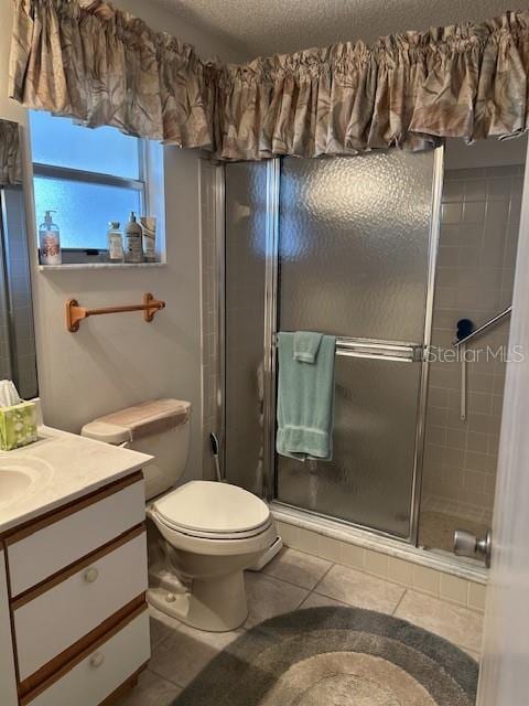 bathroom with toilet, vanity, tile patterned flooring, a textured ceiling, and a shower with door