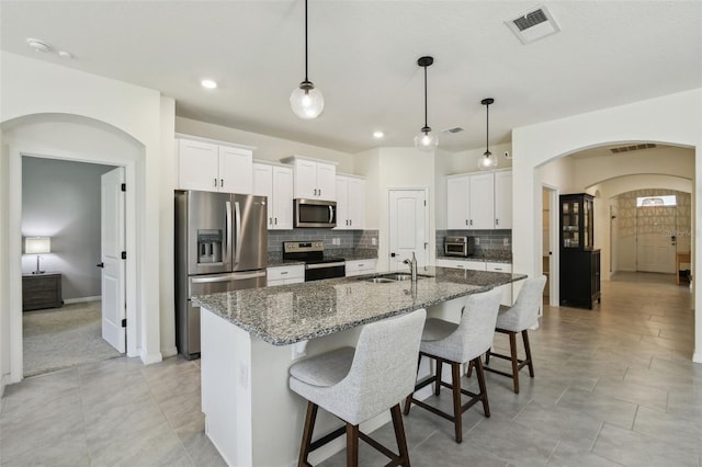 kitchen with a kitchen island with sink, sink, white cabinets, and stainless steel appliances