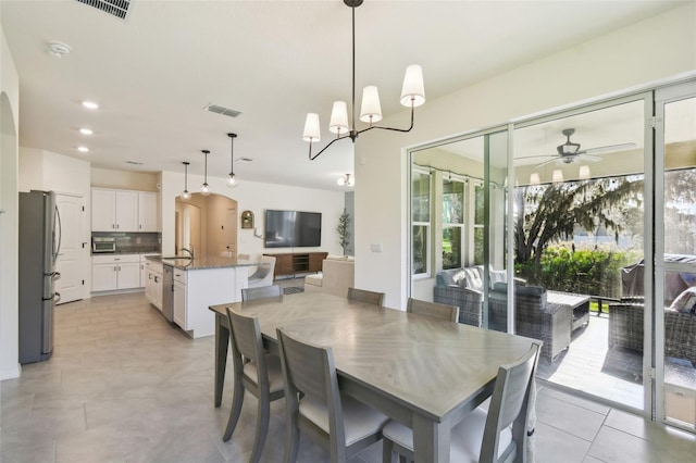 dining space featuring sink, a healthy amount of sunlight, and ceiling fan with notable chandelier