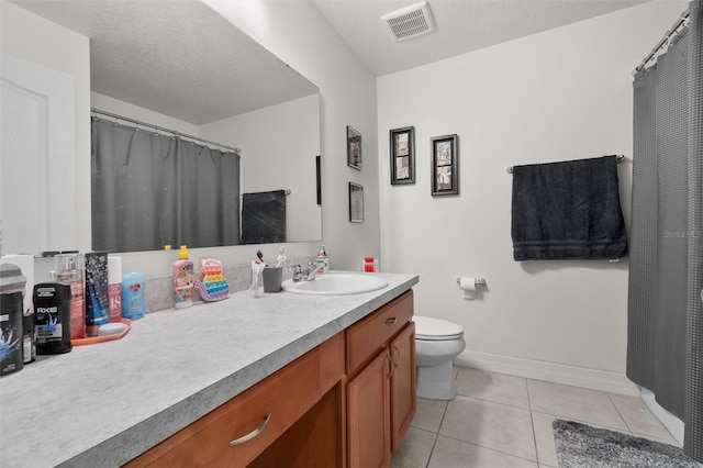 bathroom with tile patterned flooring, vanity, a textured ceiling, and toilet