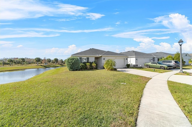 ranch-style house featuring a front yard, a water view, and a garage