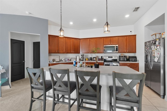 kitchen with stainless steel appliances, a kitchen island with sink, hanging light fixtures, and sink