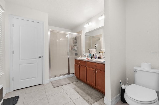 bathroom with toilet, vanity, tile patterned floors, and a shower with shower door