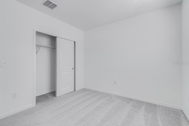 unfurnished bedroom featuring light carpet and a closet