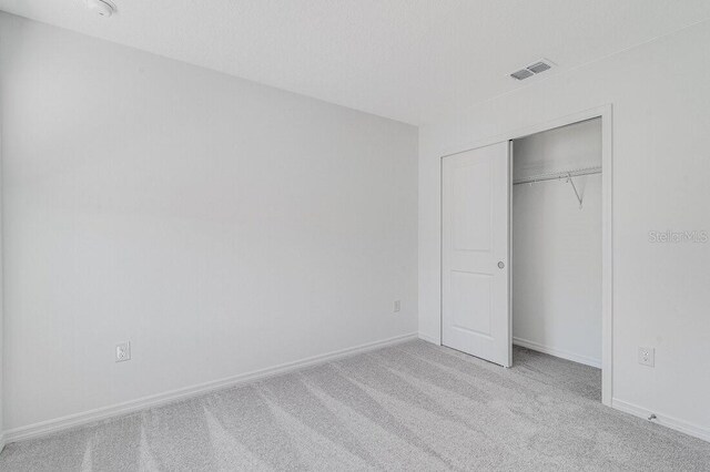 unfurnished bedroom with a closet and light carpet