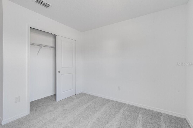 unfurnished bedroom featuring light colored carpet and a closet