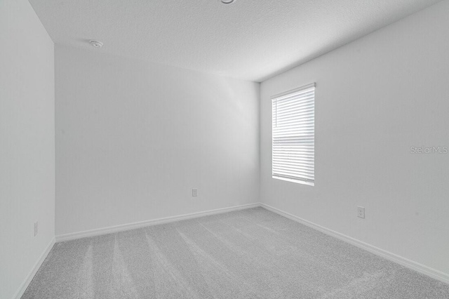 empty room featuring a textured ceiling and carpet flooring