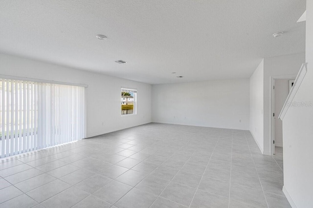 spare room featuring light tile patterned flooring and a textured ceiling