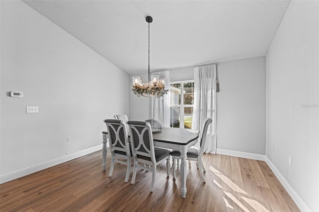 dining room with hardwood / wood-style flooring, a notable chandelier, and a textured ceiling