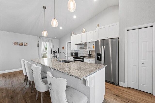 kitchen with appliances with stainless steel finishes, white cabinetry, a kitchen island with sink, and pendant lighting