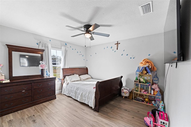 bedroom with ceiling fan, light hardwood / wood-style floors, and a textured ceiling