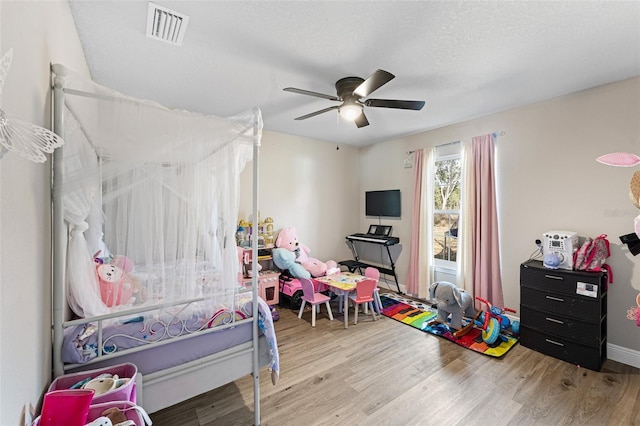 bedroom with a textured ceiling, light wood-type flooring, and ceiling fan