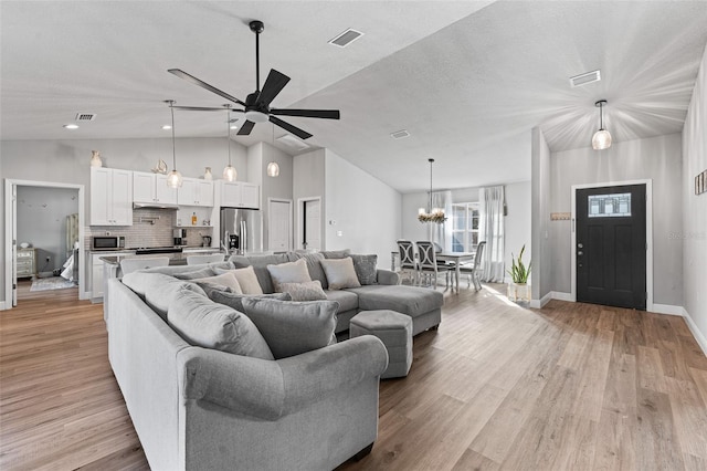 living room featuring ceiling fan, light wood-type flooring, lofted ceiling, and a textured ceiling