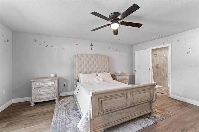 bedroom featuring a textured ceiling, hardwood / wood-style flooring, ensuite bath, and ceiling fan