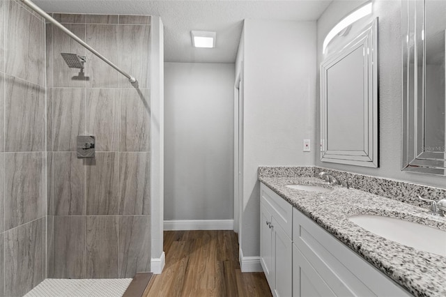 bathroom with hardwood / wood-style flooring, vanity, tiled shower, and a textured ceiling